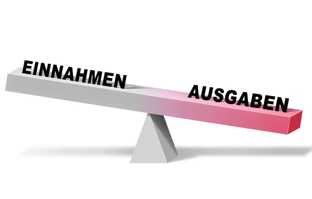 Das Bild zeit eine Waage. Auf der einen Seite ist das Wort Einnahmen und auf der anderen Seite das Wort Ausgaben zu sehen. Die Waage ist so gekippt, dass das Wort Ausgaben unten ist und die Einnahmen oben. Der Hintergrund ist weiß.
