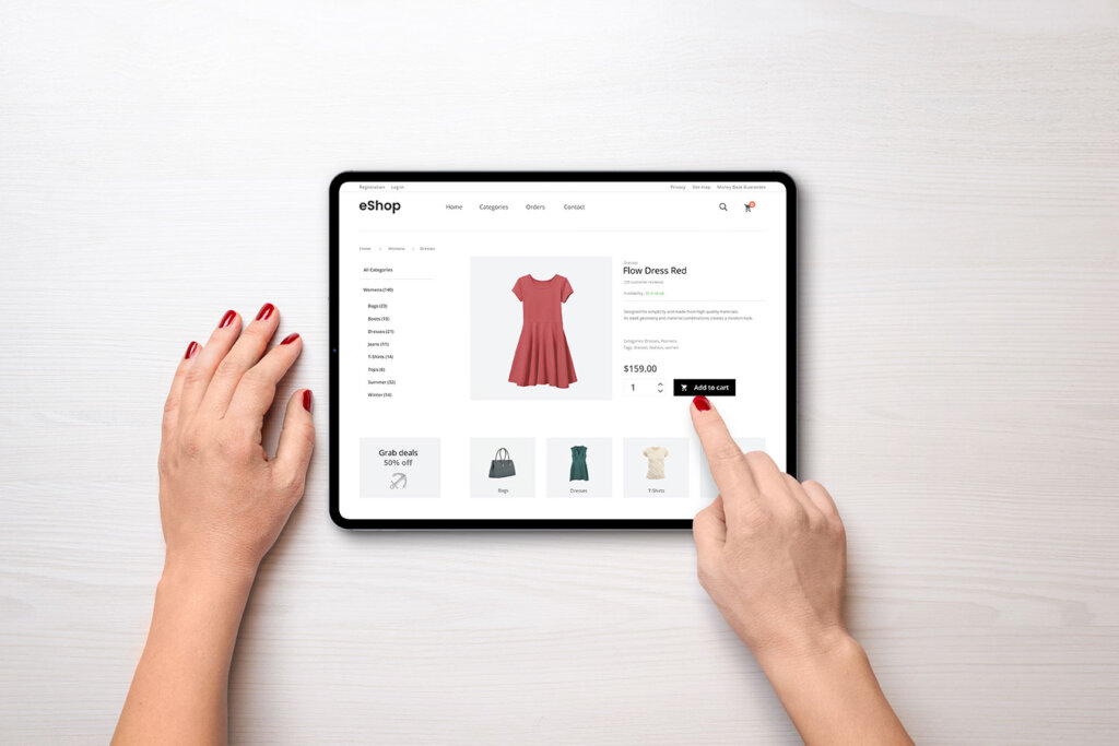 Tipps für den E-Commerce. Das Bild zeigt in Draufsicht einen Tablet, auf dessen Bildschirm ein Webshop zu sehen ist. Eine Person klickt auf ein Item, um es in den digitalen Warenkorb zu legen.